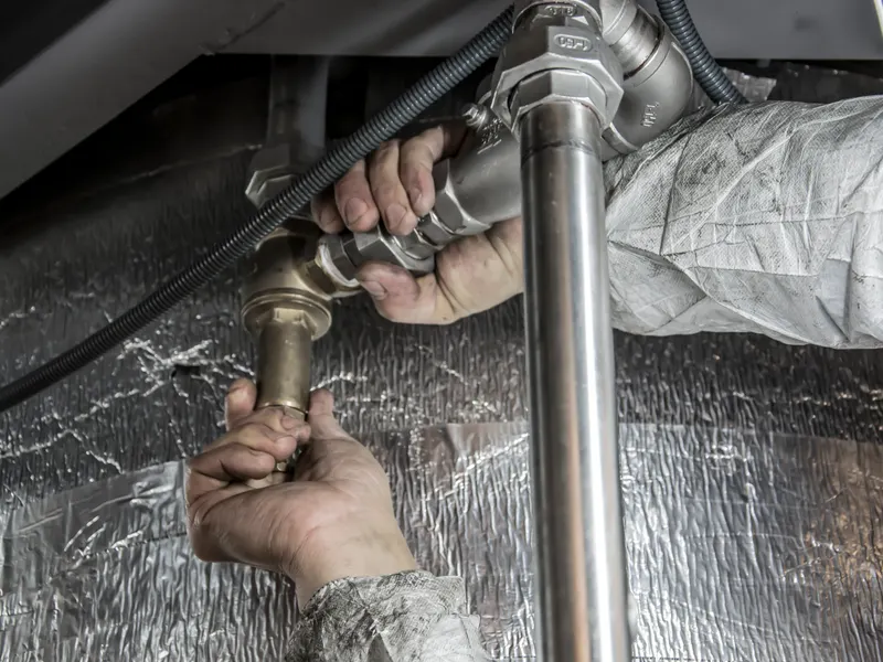 Plumber repairing a copper pipe fitting with a wrench in Colorado Springs, CO